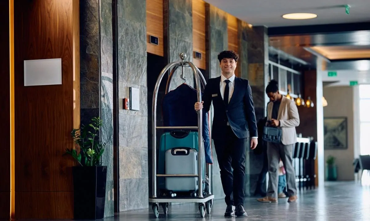 hotel-attendant-pushing-luggage-cart-in-a-lobby hotel-attendant-pushing-luggage-cart-in-a-lobby