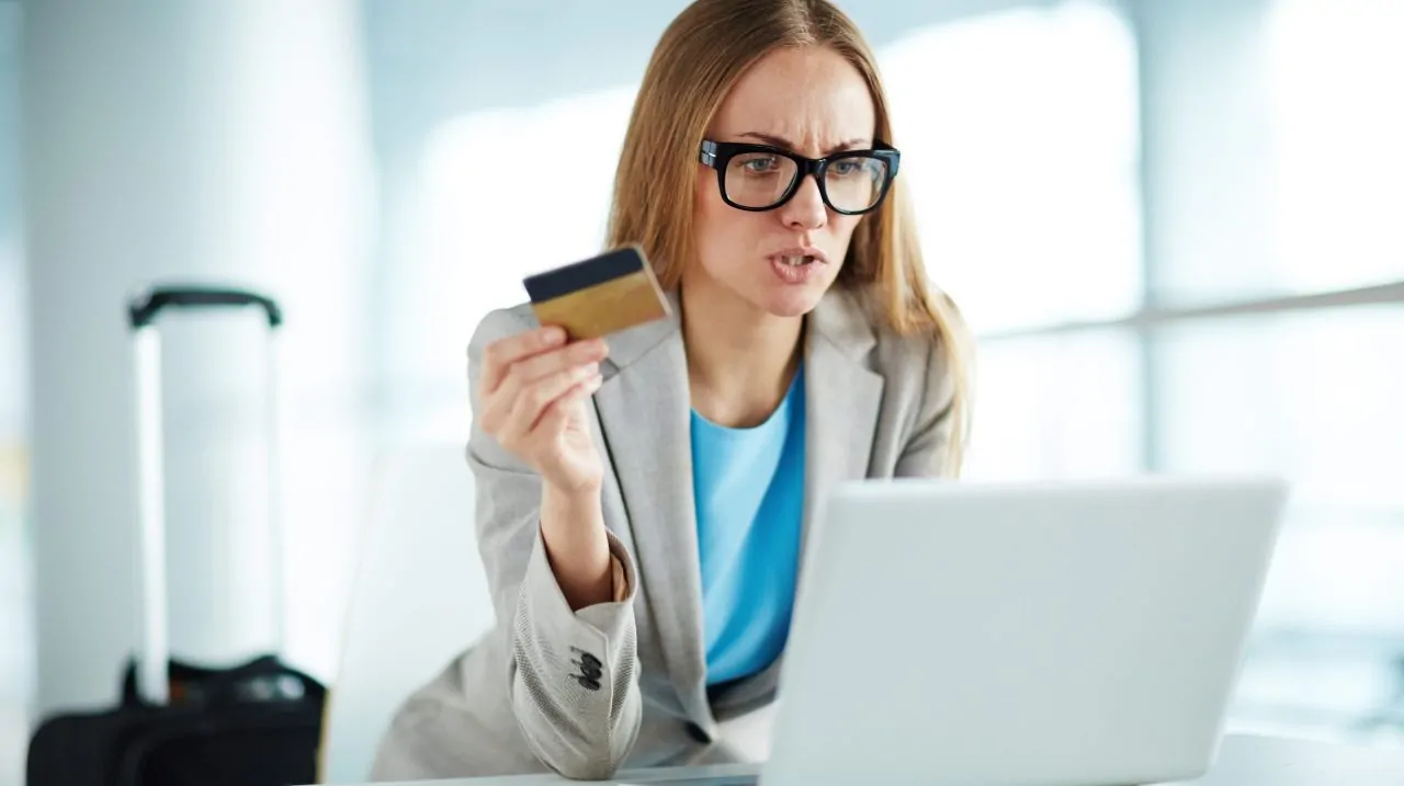 Angry businesswoman with credit card at laptop